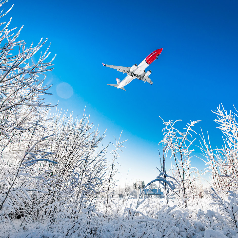 Avión de Norwegian volando sobre campos nevados