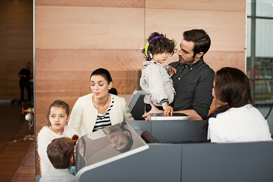 Familia con niños pequeños hablando en el check-in de un aeropuerto